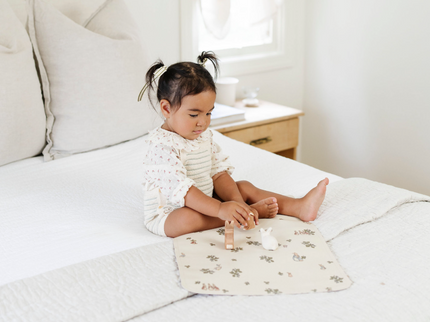 Image of a small girl playing with toys in bed